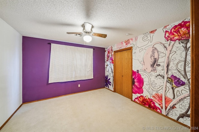 carpeted empty room featuring ceiling fan and a textured ceiling