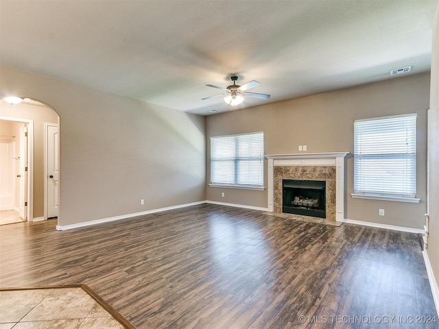 unfurnished living room featuring a premium fireplace, ceiling fan, and dark hardwood / wood-style floors