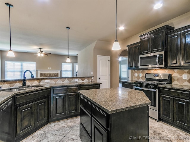 kitchen with decorative light fixtures, a center island, stainless steel appliances, and sink