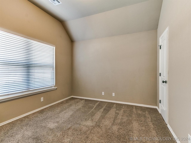 carpeted empty room with vaulted ceiling