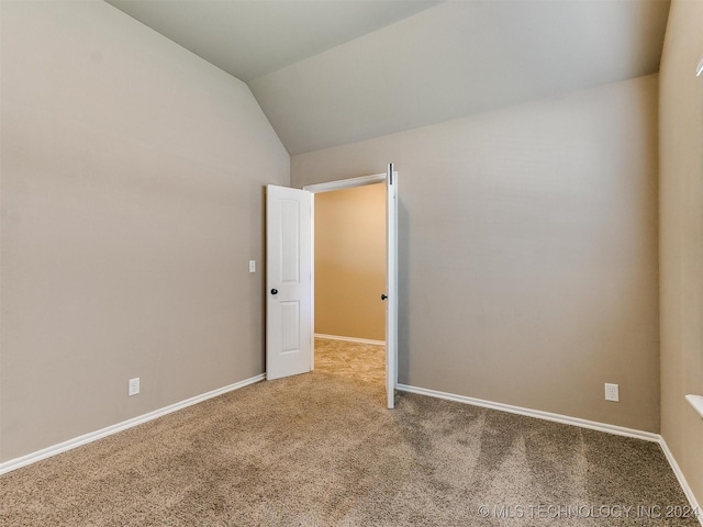 carpeted empty room featuring vaulted ceiling