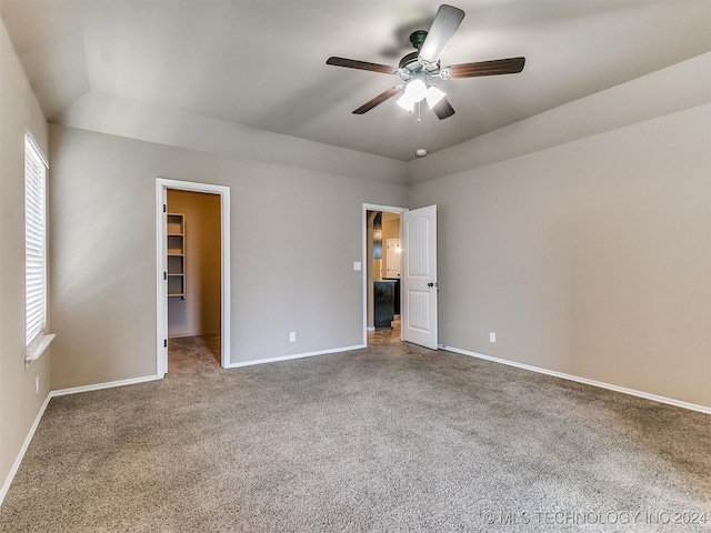 unfurnished bedroom with a walk in closet, ceiling fan, carpet, and multiple windows