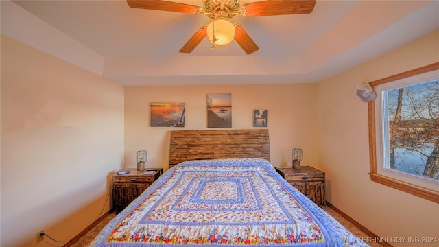 bedroom with hardwood / wood-style flooring, ceiling fan, and a tray ceiling