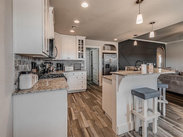 kitchen with a center island with sink, white cabinets, decorative light fixtures, light hardwood / wood-style floors, and stainless steel appliances