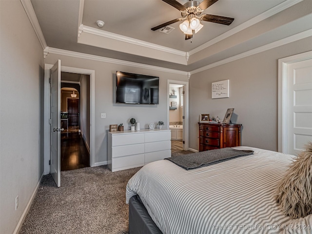 bedroom featuring dark colored carpet, ensuite bathroom, a raised ceiling, crown molding, and ceiling fan