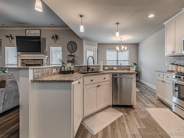 kitchen featuring white cabinets, hanging light fixtures, appliances with stainless steel finishes, and light hardwood / wood-style flooring