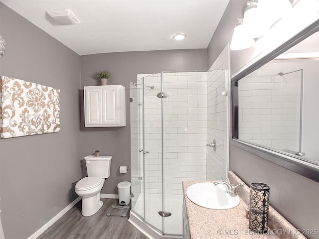 bathroom with toilet, vanity, a shower with door, and hardwood / wood-style floors