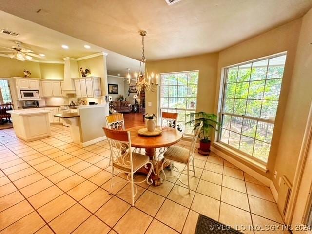 tiled dining area featuring ceiling fan with notable chandelier and ornamental molding