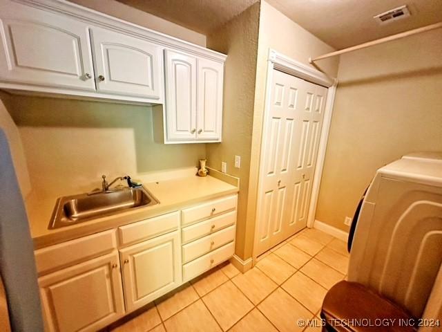 clothes washing area featuring light tile patterned flooring, cabinets, sink, and washer / clothes dryer