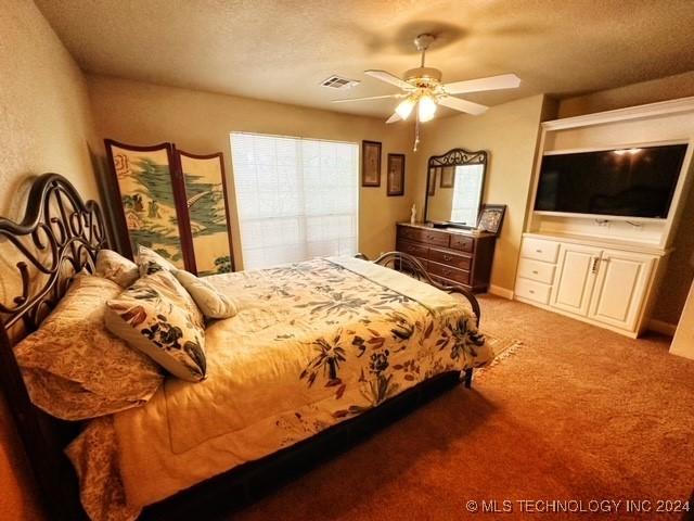 bedroom featuring a textured ceiling, ceiling fan, and light carpet