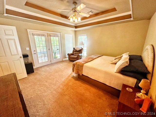 carpeted bedroom featuring a raised ceiling, ceiling fan, and access to outside