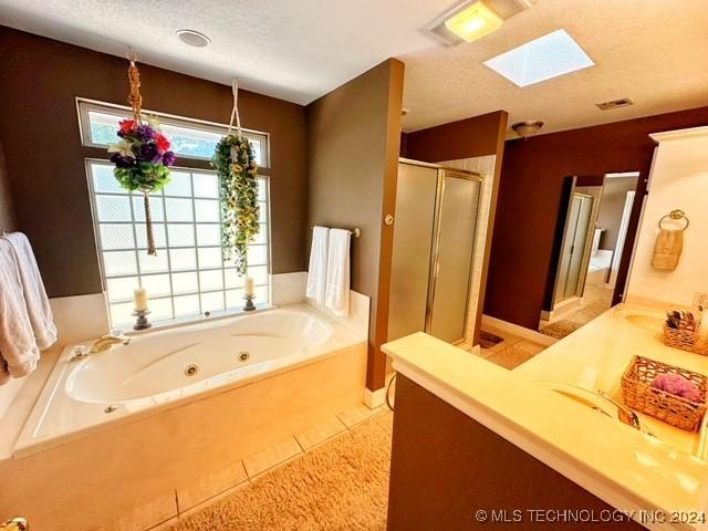 bathroom with tile patterned flooring, a textured ceiling, a skylight, and independent shower and bath