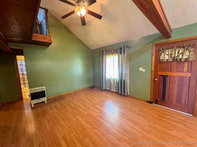 unfurnished living room featuring lofted ceiling with beams, light hardwood / wood-style flooring, ceiling fan, a textured ceiling, and heating unit