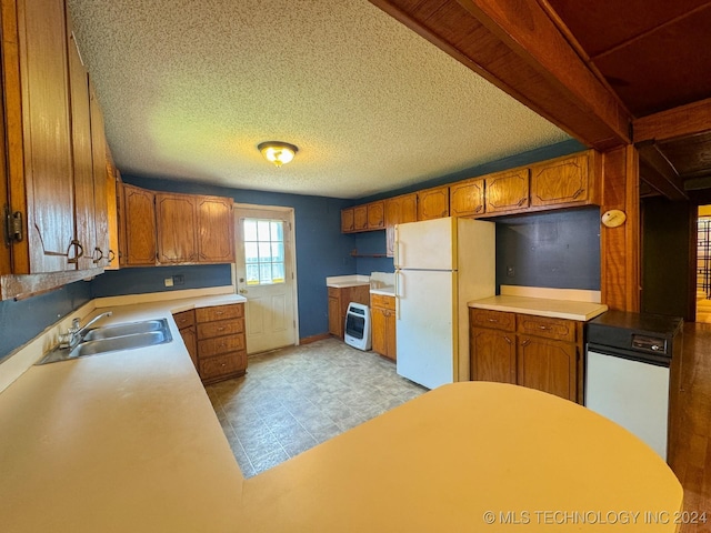 kitchen featuring beamed ceiling, sink, white fridge, and a textured ceiling