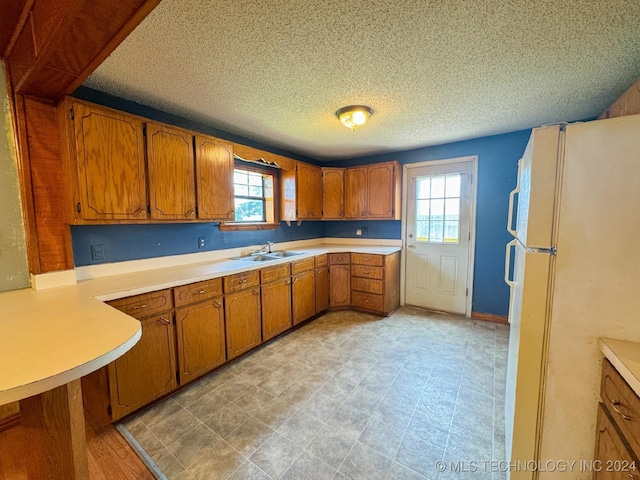 kitchen with white refrigerator, sink, and a textured ceiling