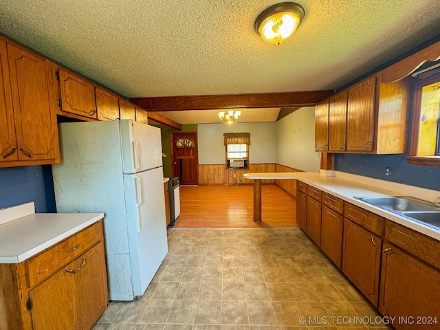 kitchen with sink, a notable chandelier, cooling unit, white fridge, and a textured ceiling