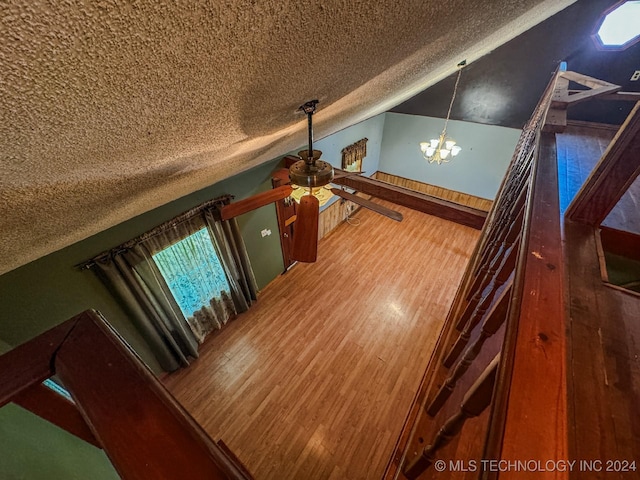 room details featuring ceiling fan with notable chandelier, a textured ceiling, and hardwood / wood-style flooring