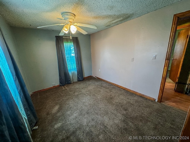 unfurnished room with ceiling fan, dark carpet, and a textured ceiling