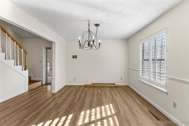 empty room featuring hardwood / wood-style flooring and an inviting chandelier