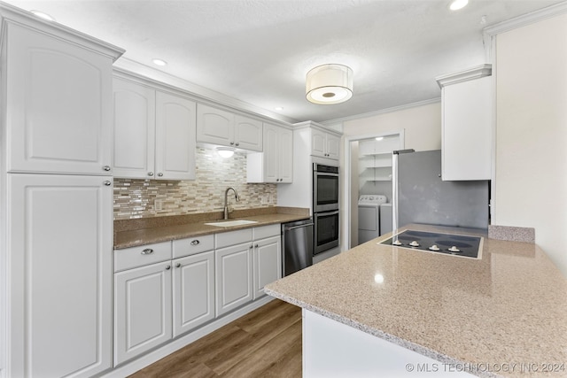 kitchen featuring sink, light wood-type flooring, independent washer and dryer, white cabinetry, and stainless steel appliances