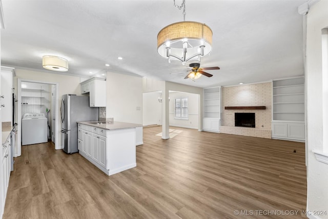 kitchen with washer / clothes dryer, light hardwood / wood-style flooring, white cabinets, and a fireplace