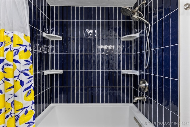 bathroom with shower / tub combo with curtain and a textured ceiling