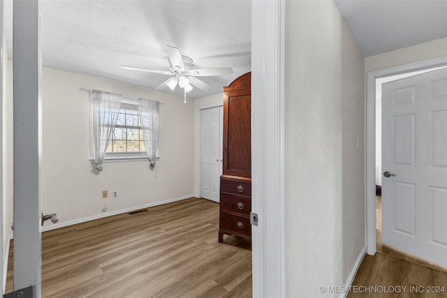 unfurnished bedroom featuring ceiling fan, light hardwood / wood-style floors, and a closet