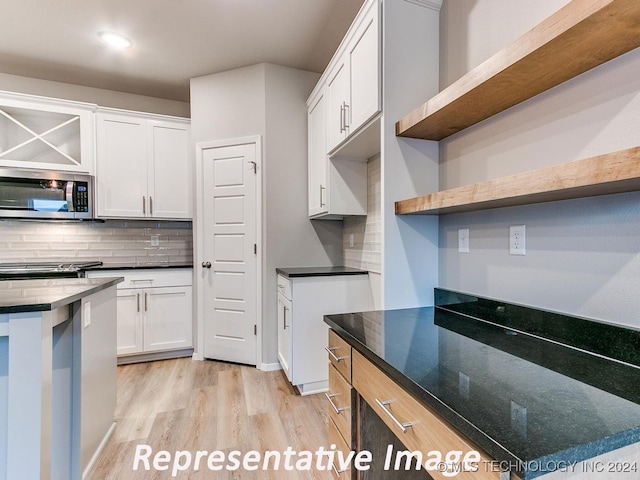 kitchen featuring tasteful backsplash, white cabinetry, light wood-type flooring, and appliances with stainless steel finishes