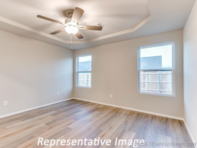 spare room featuring a tray ceiling, ceiling fan, and light hardwood / wood-style floors