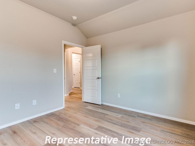 spare room featuring light hardwood / wood-style floors and vaulted ceiling