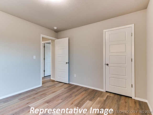 unfurnished bedroom featuring a textured ceiling and light hardwood / wood-style flooring