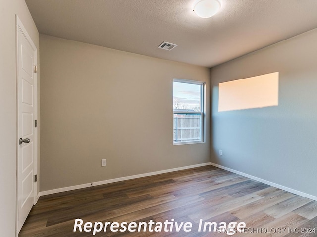 unfurnished room featuring a textured ceiling and hardwood / wood-style flooring