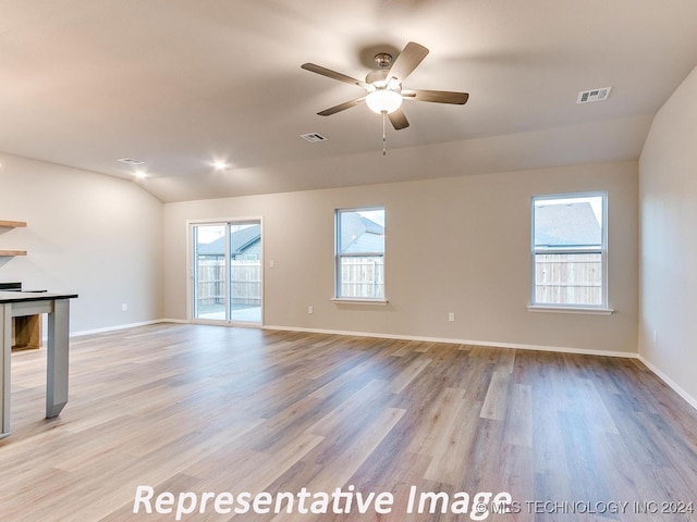 unfurnished living room with ceiling fan, lofted ceiling, and light wood-type flooring