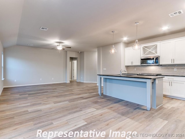 kitchen with white cabinets, decorative light fixtures, light hardwood / wood-style flooring, and tasteful backsplash