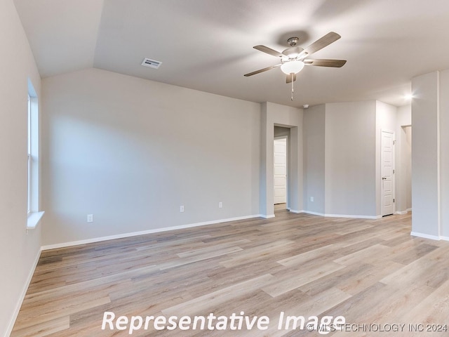 empty room with ceiling fan, vaulted ceiling, and light hardwood / wood-style flooring