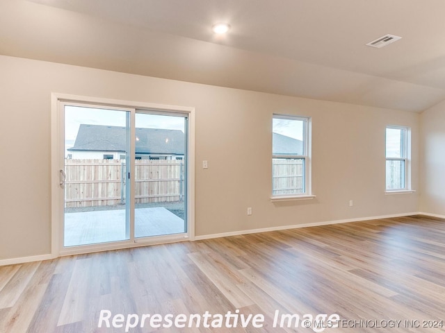 unfurnished room with lofted ceiling and light wood-type flooring