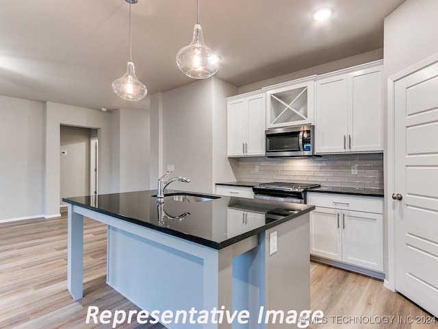 kitchen with sink, an island with sink, decorative light fixtures, white cabinetry, and stainless steel appliances