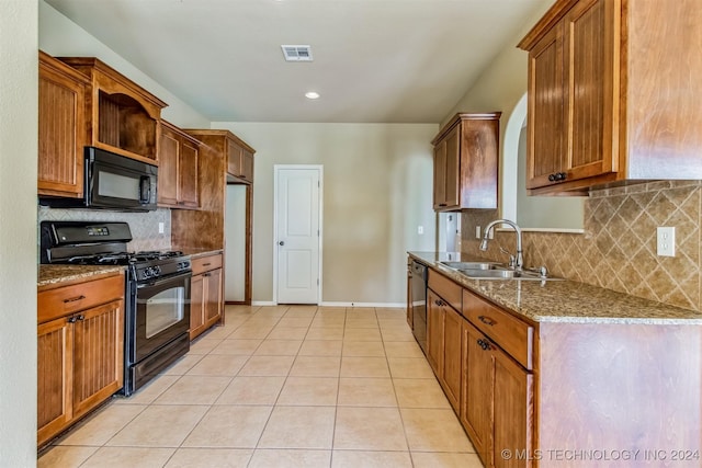 kitchen with light stone countertops, sink, decorative backsplash, light tile patterned flooring, and black appliances