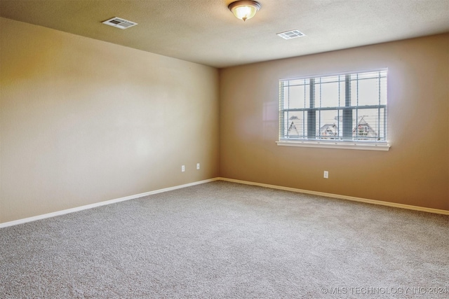 carpeted empty room featuring a textured ceiling