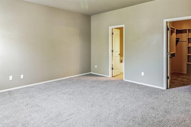 unfurnished bedroom featuring light colored carpet, a spacious closet, connected bathroom, and a closet