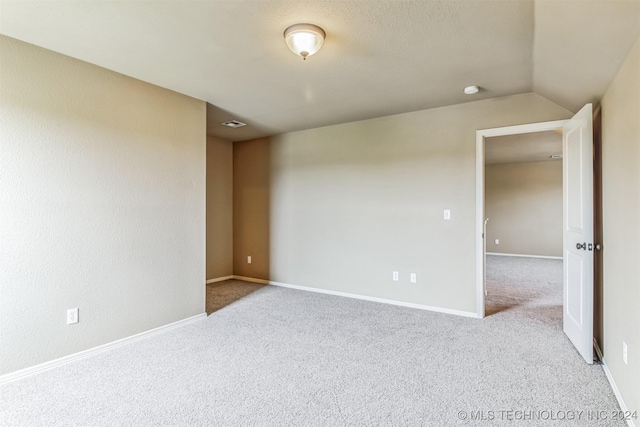 carpeted empty room featuring lofted ceiling