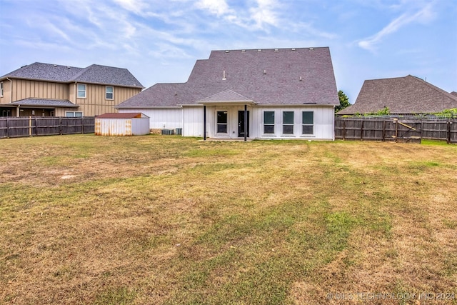 back of house featuring a yard and a shed