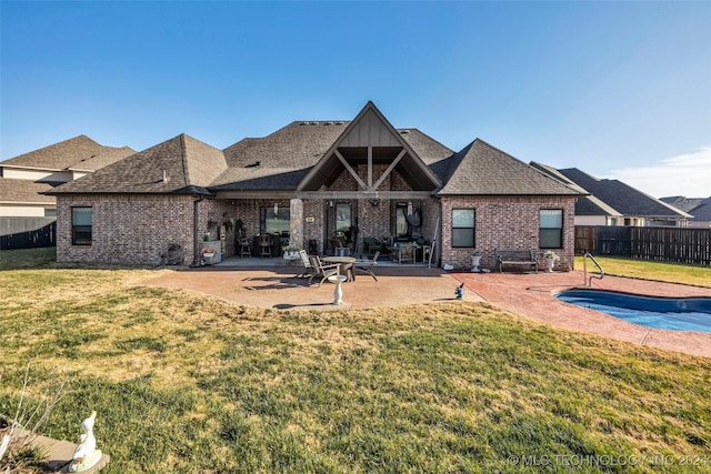 back of property with a patio area, a yard, and a fenced in pool