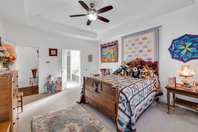 carpeted bedroom featuring a raised ceiling, ensuite bathroom, and ceiling fan