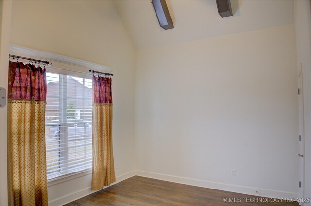 spare room with a wealth of natural light, dark hardwood / wood-style floors, and vaulted ceiling