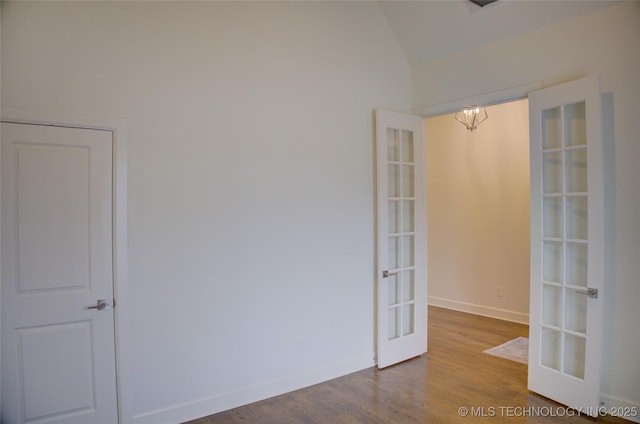 spare room with hardwood / wood-style flooring, vaulted ceiling, french doors, and a chandelier