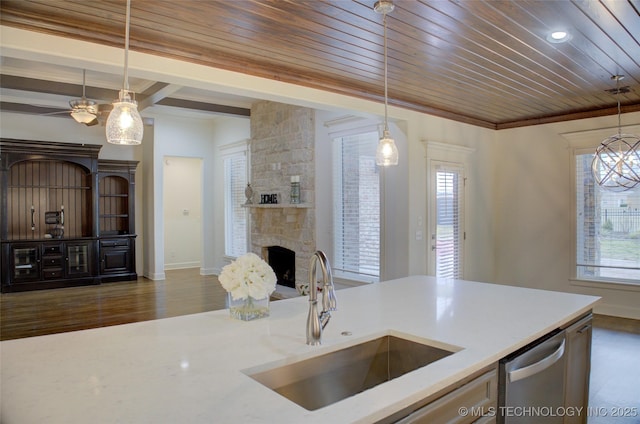 kitchen featuring sink, dishwasher, a fireplace, a wealth of natural light, and decorative light fixtures