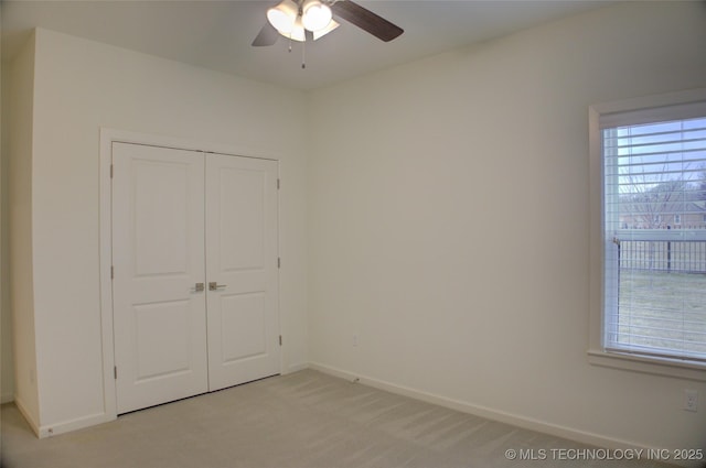 unfurnished bedroom featuring ceiling fan, a closet, and light carpet