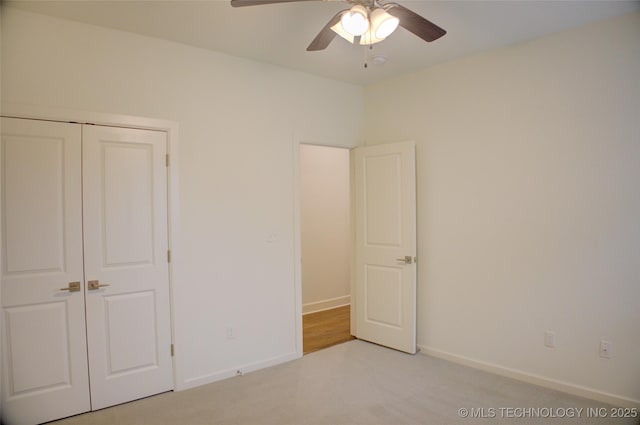 unfurnished bedroom with ceiling fan, light colored carpet, and a closet