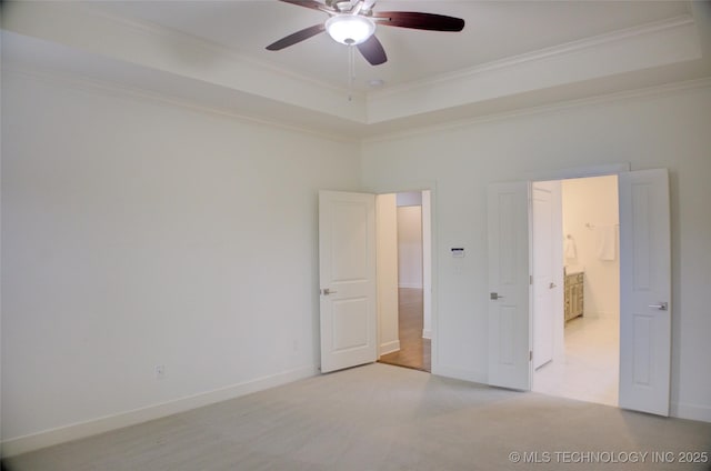 unfurnished bedroom featuring a raised ceiling, crown molding, light carpet, and ceiling fan